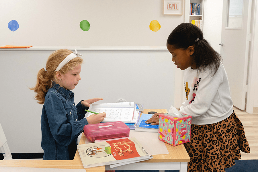 Two young students collaborate on their schoolwork, promoting team-building skills and social skills.